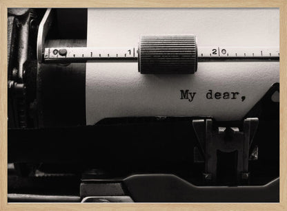 A close-up, black and white photograph of a vintage typewriter. A sheet of white paper is loaded, and the words 'My dear,' have just been typed, creating a sense of nostalgia and romance. The image is enclosed in a silver frame. Wall Art