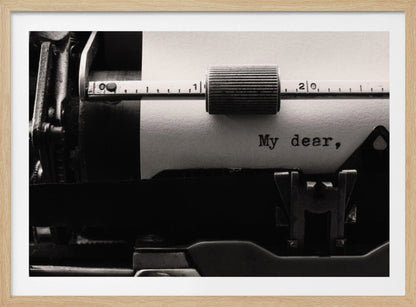 A close-up, black and white photograph of a vintage typewriter. A sheet of white paper is loaded, and the words 'My dear,' have just been typed, creating a sense of nostalgia and romance. The image is enclosed in a silver frame. Wall Art