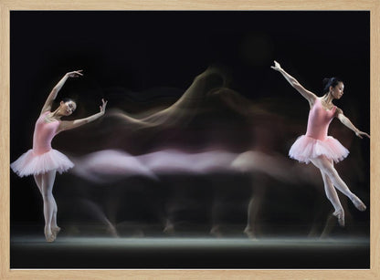 A long-exposure photograph capturing the fluid motion of a ballerina in a pink leotard and tutu. Two clear poses of the dancer frame a central, ethereal blur of movement against a dark, solid background, all encased in a silver frame. Artwork