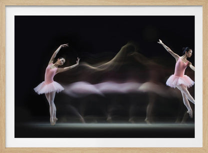 A long-exposure photograph capturing the fluid motion of a ballerina in a pink leotard and tutu. Two clear poses of the dancer frame a central, ethereal blur of movement against a dark, solid background, all encased in a silver frame. Artwork