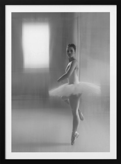 A black and white artistic photograph of a ballerina in a white leotard and tutu, mid-pose on pointe. The image has a motion blur effect, creating a dreamy and ethereal atmosphere as she glances back at the camera. Decor