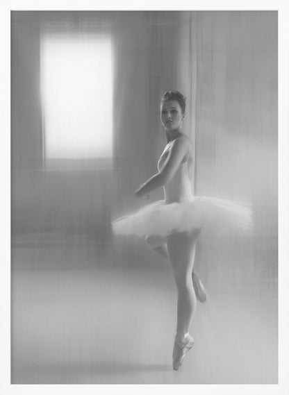 A black and white artistic photograph of a ballerina in a white leotard and tutu, mid-pose on pointe. The image has a motion blur effect, creating a dreamy and ethereal atmosphere as she glances back at the camera. Decor