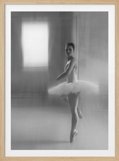 A black and white artistic photograph of a ballerina in a white leotard and tutu, mid-pose on pointe. The image has a motion blur effect, creating a dreamy and ethereal atmosphere as she glances back at the camera. Decor