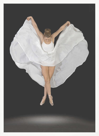 A high-angle studio photograph of a graceful ballet dancer suspended mid-air against a solid black background. She wears a white leotard and pointe shoes, with her legs crossed. Her arms are outstretched, holding a large, flowing white fabric that creates a shape like wings around her. Decor
