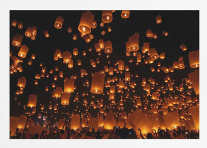 A framed photograph of a sky lantern festival at night, with hundreds of warm, orange-glowing lanterns floating up into the pitch-black sky from a crowd of people below. Artwork