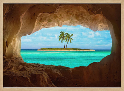 A framed artwork depicting a view from inside a rocky cave looking out at a small tropical island with two palm trees. The cave's natural arch frames the vibrant turquoise ocean and the bright blue sky, creating a sense of a hidden paradise. Artwork