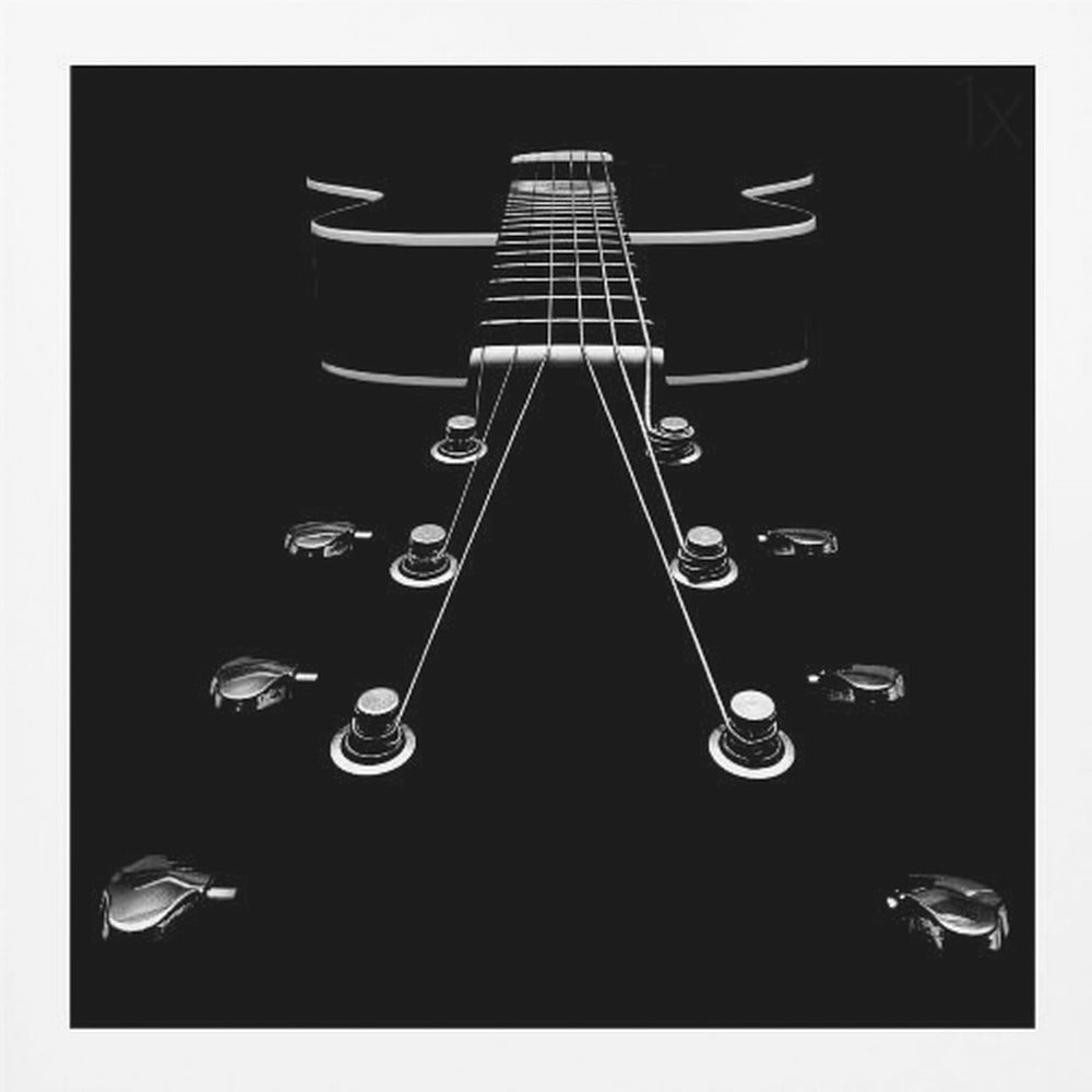 A dramatic, low-angle, black and white photograph of an electric guitar. The perspective looks up from the headstock, with the shiny tuning pegs and strings creating strong leading lines towards the fretboard and body, which are outlined in white against a solid black background. Poster