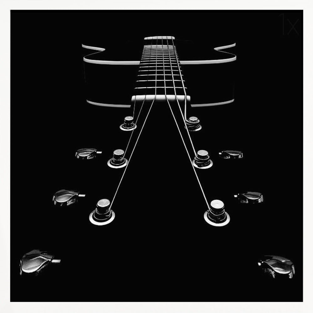A dramatic, low-angle, black and white photograph of an electric guitar. The perspective looks up from the headstock, with the shiny tuning pegs and strings creating strong leading lines towards the fretboard and body, which are outlined in white against a solid black background. Poster