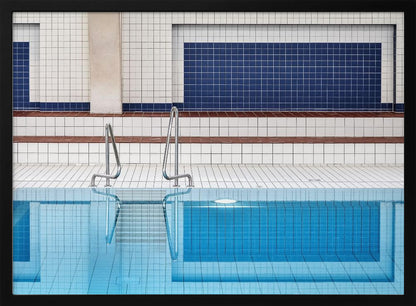 A framed, symmetrical photograph of a minimalist indoor swimming pool with blue and white tiles, stainless steel ladders, and a calm, reflective water surface. Poster