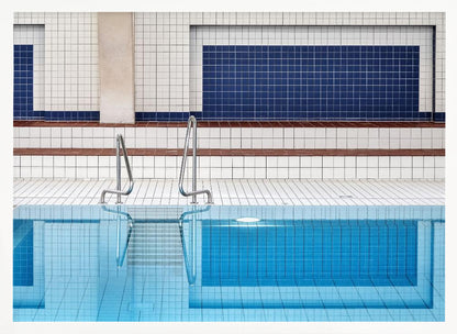A framed, symmetrical photograph of a minimalist indoor swimming pool with blue and white tiles, stainless steel ladders, and a calm, reflective water surface. Poster