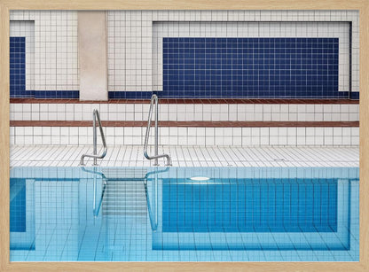 A framed, symmetrical photograph of a minimalist indoor swimming pool with blue and white tiles, stainless steel ladders, and a calm, reflective water surface. Poster