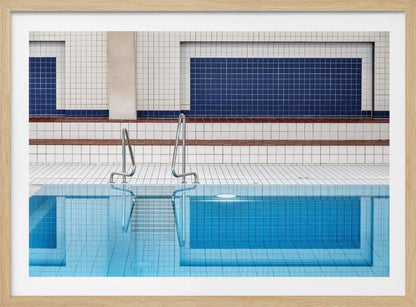A framed, symmetrical photograph of a minimalist indoor swimming pool with blue and white tiles, stainless steel ladders, and a calm, reflective water surface. Poster