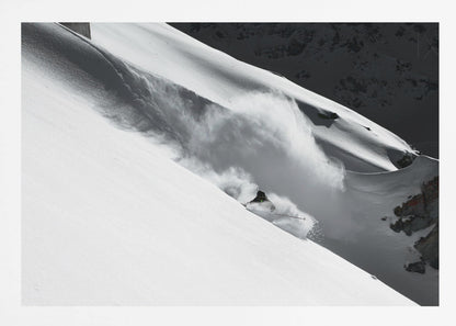 A dramatic black and white photograph of a skier speeding down a steep, snow-covered mountain, kicking up a large cloud of powder. The image is framed with a brushed silver border. Decor