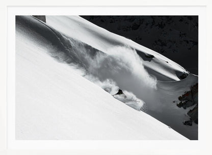 A dramatic black and white photograph of a skier speeding down a steep, snow-covered mountain, kicking up a large cloud of powder. The image is framed with a brushed silver border. Decor