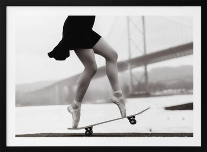 A black and white photograph of a ballerina's legs in a black dress, balancing en pointe on a skateboard with a blurred bridge in the background. Artwork