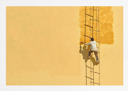 A man viewed from behind stands on a rope ladder, painting a large, bright yellow wall a slightly darker shade of yellow, casting a stark shadow in the bright sun. The image is presented within a silver frame. Decor