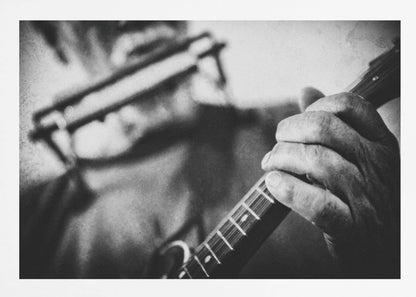 A grainy, black and white close-up photograph of a musician's hand gripping the neck of a stringed instrument. The focus is on the hand and the frets, with the musician's body and face softly blurred in the background. The image is enclosed in a silver frame. Wall Art