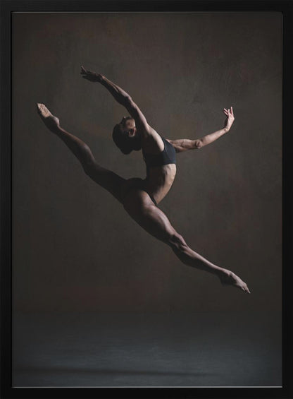 A dramatic, low-key studio photograph of a muscular female dancer captured mid-leap. She is in a full split, arching her back with her arms extended gracefully. The lighting accentuates her toned physique against a dark, textured brown background. Poster