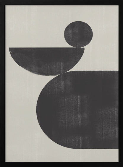 A minimalist abstract artwork featuring three charcoal black shapes stacked against a light beige textured background. At the bottom is a large, rounded shape, on which a semi-circle is balanced. A smaller, full circle rests on top of the semi-circle, creating a sense of precarious balance. The piece is enclosed in a simple black frame. Decor