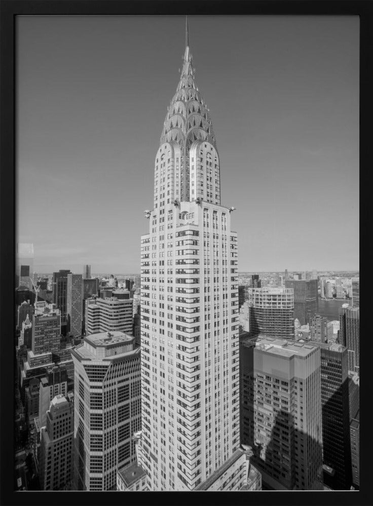 A high-angle, black and white photograph of the iconic Chrysler Building, its Art Deco spire prominently featured against the New York City skyline under a clear sky. Artwork