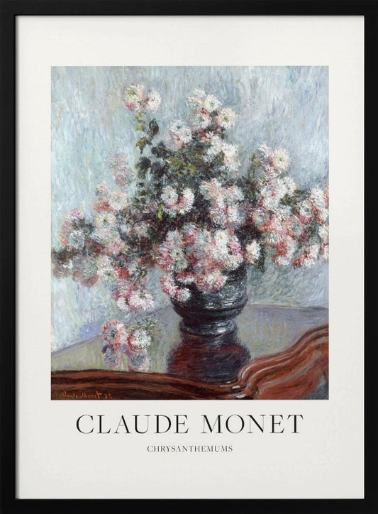 A framed art print of Claude Monet's impressionist painting, 'Chrysanthemums.' The painting features a lush bouquet of pink and white chrysanthemums in a dark vase resting on a reflective, mahogany-colored table against a light blue, textured background. The print includes a white border with the artist's name and the title below the artwork, all enclosed in a simple black frame. Print