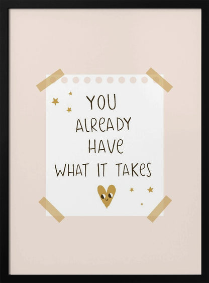 A motivational poster in a black frame with a pale pink background. A white piece of notebook paper is taped to the center with the handwritten text 'YOU ALREADY HAVE WHAT IT TAKES' in brown. It's decorated with small gold stars and a cute, smiling gold heart. Decor