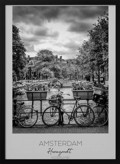 A black and white poster of the Herengracht canal in Amsterdam. In the foreground, two bicycles are parked by a railing with flower boxes. In the background, there's a classic view of the canal with a bridge, canal houses, and boats under a cloudy sky. The bottom of the poster has text that reads 'AMSTERDAM Herengracht NEDERLAND'. Decor