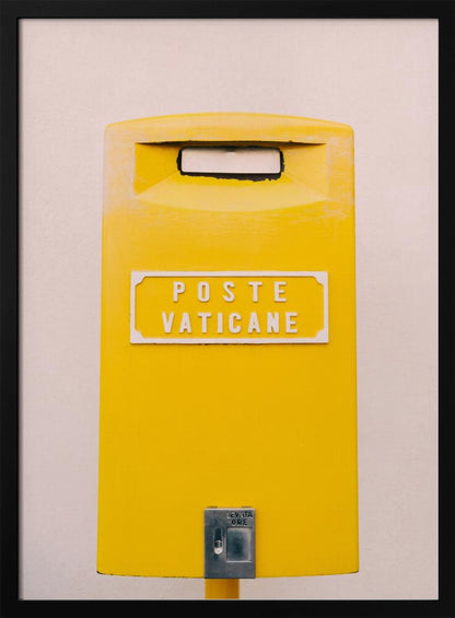 A close-up, front-view photograph of a vibrant yellow Vatican City mailbox against a plain beige wall, enclosed in a thin black frame. The words 'POSTE VATICANE' are printed in white on the front. Artwork