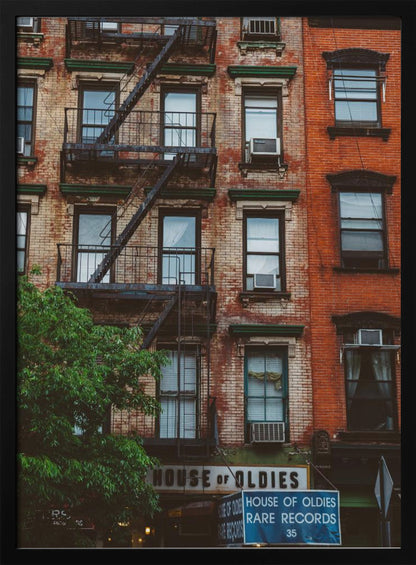 A classic multi-story brick apartment building with a prominent black metal fire escape zigzagging across its facade. A sign for a 'House of Oldies' rare records shop is visible on the ground floor. Poster