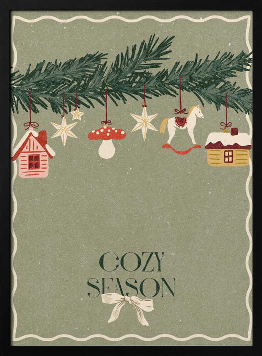 A vintage-style holiday poster with a sage green background. A pine branch hangs at the top, decorated with illustrated ornaments including houses, stars, a mushroom, and a rocking horse. Below, the text 'COZY SEASON' is written in a dark serif font with a light-colored bow underneath. Artwork