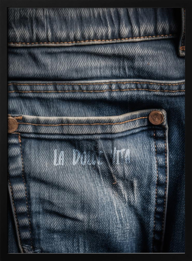 A detailed close-up photograph of a faded blue jean back pocket, showing the texture of the denim, orange stitching, and a copper rivet. Faint white text is stenciled onto the pocket. Poster