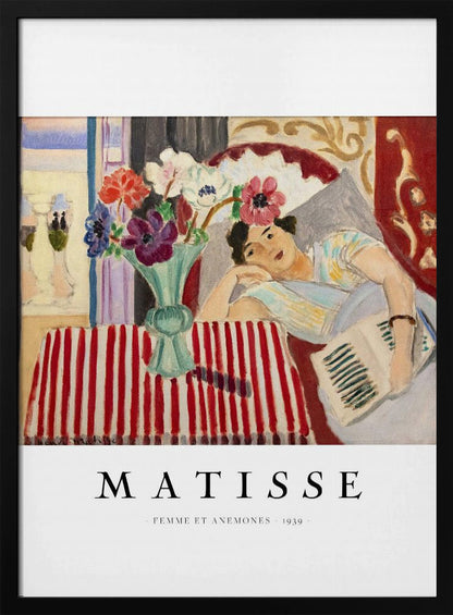 A poster featuring Henri Matisse's 1939 painting, 'Femme et Anemones'. The artwork depicts a woman in a colorful top reclining on a couch, holding a book. Beside her, on a red and white striped tablecloth, sits a vase filled with vibrant anemone flowers. The poster has a black frame and white matting, with 'MATISSE' printed below the image. Artwork