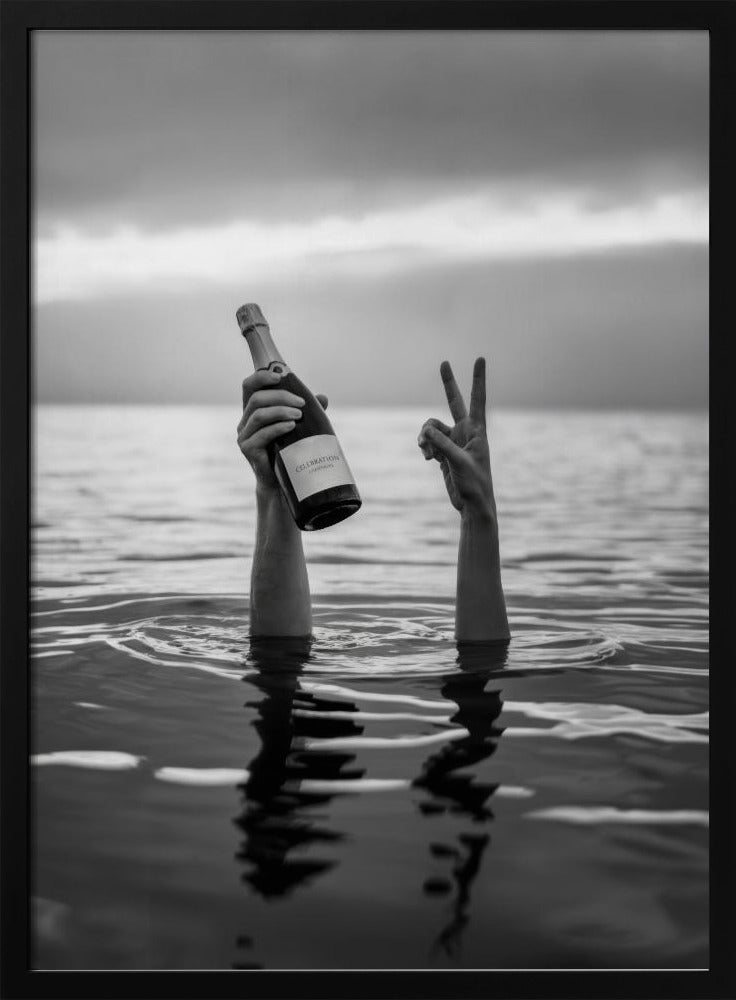 A black and white vertical photograph showing two arms sticking out of calm water. One hand holds a bottle of champagne, while the other makes a peace sign, all under a cloudy sky. Poster