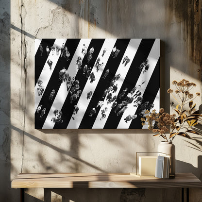 A striking black and white aerial photograph of dozens of people walking across a large, diagonally striped crosswalk. The high-contrast, graphic pattern of black and white stripes dominates the scene, with the small figures of pedestrians scattered across it, creating a sense of movement and urban anonymity. The image is presented within a simple silver frame. Print