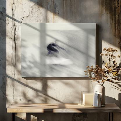 An artistic black and white photograph using motion blur to capture a surfer in a dynamic, fluid pose on a wave. The slow shutter speed creates a sense of speed and abstract movement, with the surfer's dark wetsuit contrasting against the white, streaked water. The image is presented in a silver frame. Decor