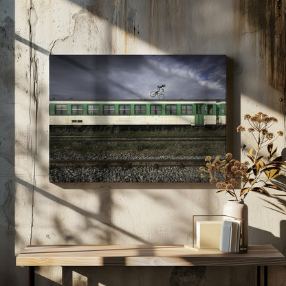 A BMX rider is captured in mid-air performing a stunt on the roof of a green and white passenger train car, set against a dramatic, stormy sky. The scene takes place on railway tracks with gravel and overgrown grass, and the entire image is enclosed in a silver frame. Decor