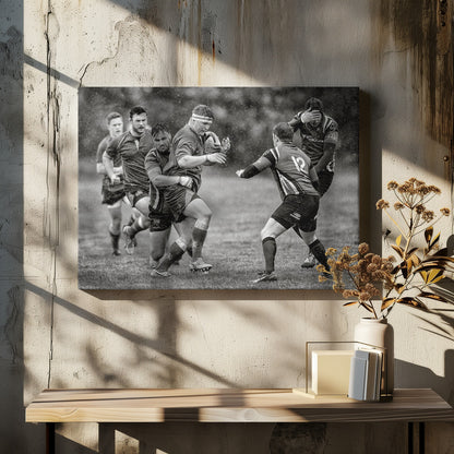 A dynamic black and white photograph of a rugby match being played in the rain. One player charges forward with the ball while an opponent wraps his arms around him in a tackle. Other players are in motion around them, capturing the intensity and physicality of the sport. Decor