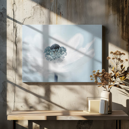 A dreamy, soft-focus macro photograph of a single white anemone flower. The flower has a dark center surrounded by delicate blue-tipped stamens. The background is a soft, pale blue, and the entire image is presented within a silver frame. Wall Art