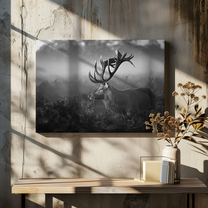 A majestic stag with large antlers is captured in a black and white photograph, standing in a field of ferns with a foggy forest in the background. The image has a moody and atmospheric quality and is displayed within a silver frame. Poster