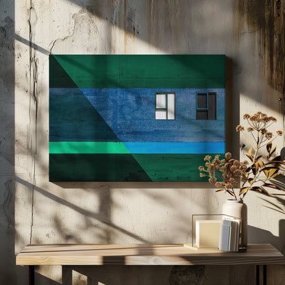 A framed abstract architectural photograph featuring a color-blocked facade. A central horizontal band of textured blue wall contains two small, distinct windows. This is flanked by upper and lower sections of dark green. A large, dark diagonal shape overlays the left side of the composition, creating sharp geometric lines. Decor
