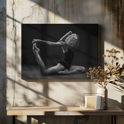 A black and white studio photograph of a flexible ballerina in a dark leotard and pointe shoes, arching her back to hold her extended leg over her head in an elegant pose against a dark background. Artwork