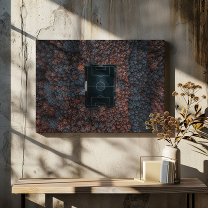 An aerial top-down photograph of a stark black soccer field with white markings, dramatically set in the middle of a dense, colorful forest with blue and rust-colored trees, all enclosed within a silver frame. Wall Art