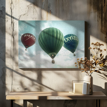 A low-angle photograph of three colorful hot air balloons floating in a cloudy blue sky, presented in a silver frame. A large green balloon is in the center, with a red balloon on the left and a dark blue balloon on the right, all featuring logos. Wall Art
