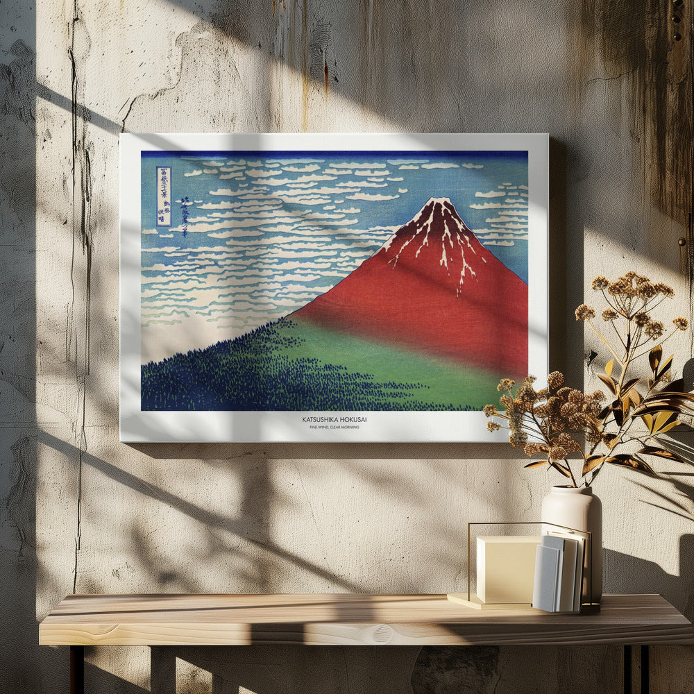 A framed Japanese woodblock print, 'Fine Wind, Clear Morning' by Katsushika Hokusai, also known as 'Red Fuji'. The print depicts a large, reddish-brown Mount Fuji with its peak lightly dusted with snow, set against a vibrant blue sky filled with white, streaky clouds. A dark green forest covers the base of the mountain. Poster