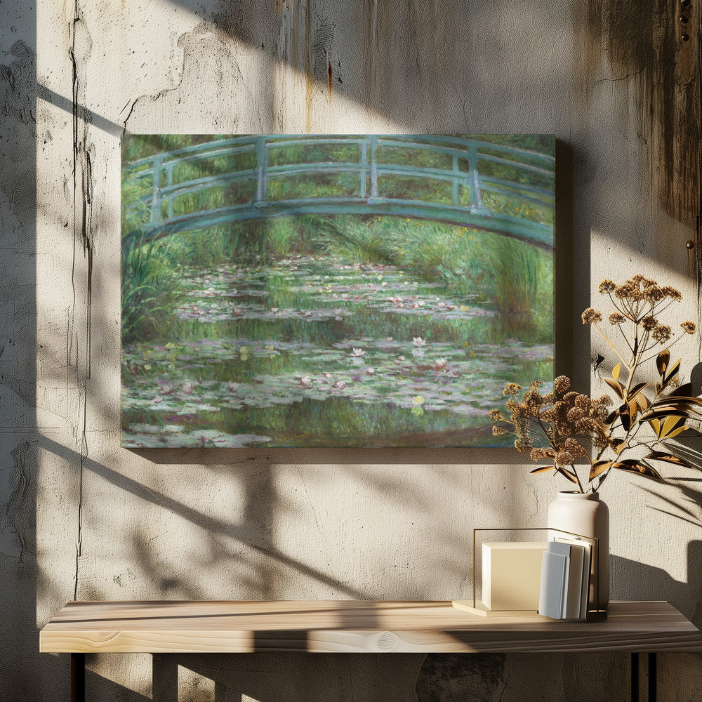 An Impressionist painting by Claude Monet depicting a green Japanese-style footbridge arching over a tranquil pond filled with blooming water lilies and lily pads, all rendered in soft, dappled brushstrokes and framed in a modern silver frame. Print