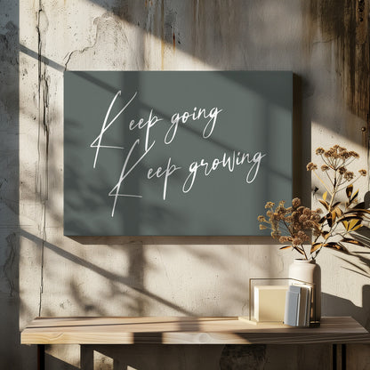 A motivational art piece featuring the words 'Keep going' and 'Keep growing' in a delicate white script on a muted sage green background, set within a simple silver frame. Print