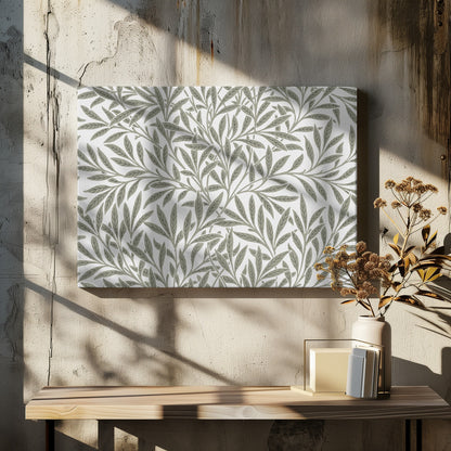 A framed art print displaying a dense pattern of sage green leaves and branches on a white background. The design is continuous and has a calm, naturalistic feel, enclosed within a simple silver frame. Artwork