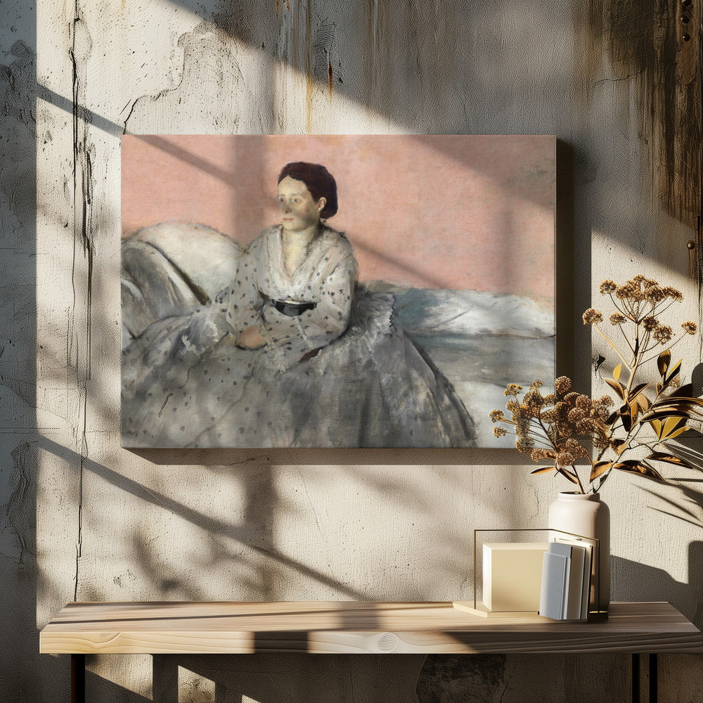 A framed impressionist painting titled 'Mélancolie' by Edgar Degas, depicting a woman with dark hair pulled back, seated on a couch or bed. She wears a white and grey polka-dotted dress with a black sash and has a pensive expression, looking off to the side against a soft pink background. Decor