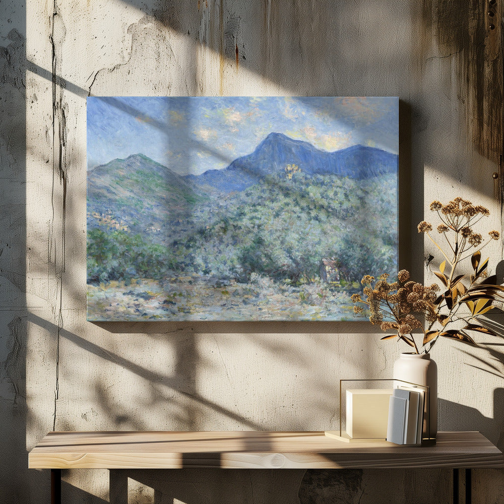 An Impressionist painting by Claude Monet, 'Valle Buona, near Bordighera', showcasing a vast landscape of rolling green hills and deep blue mountains under a light blue sky with wispy clouds. The painting, rendered in soft, textured brushstrokes, is presented in a simple silver frame. Print