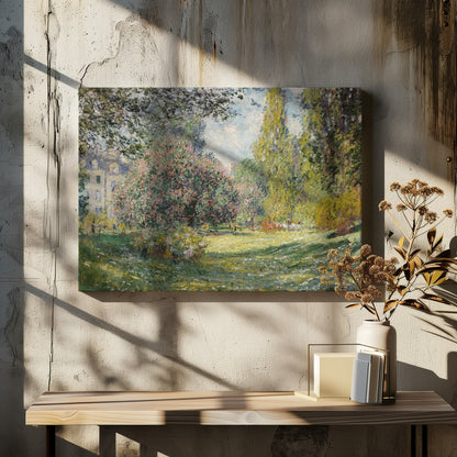 An impressionist painting by Claude Monet titled 'The Parc Monceau' displayed in a silver frame. The scene depicts a sunlit park with lush green grass, a large pink-flowering bush, and tall, leafy trees under a pale blue sky. Decor